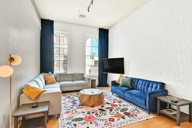A living room at 3rd Street Retreat with a blue sofa, a patterned rug and arched windows