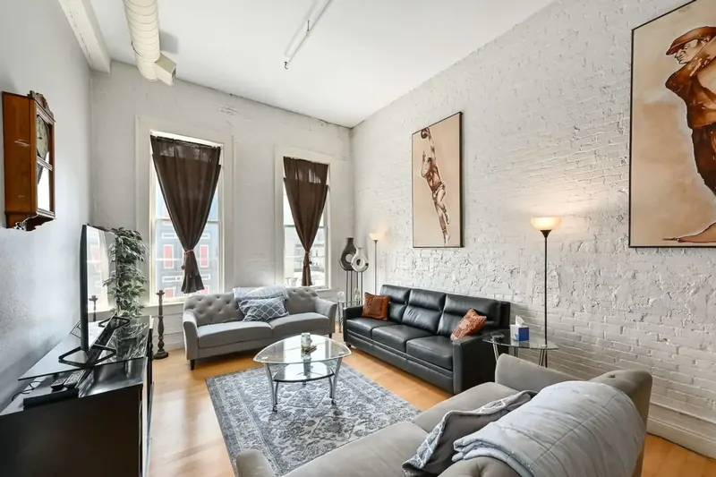 A loft living room with brick walls, tall windows and two sofas at 3rd Street Retreat