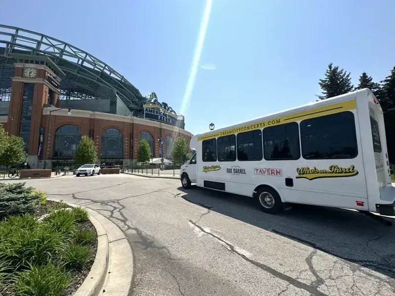 The white shuttle bus turning in front of American Family Field on a sunny day