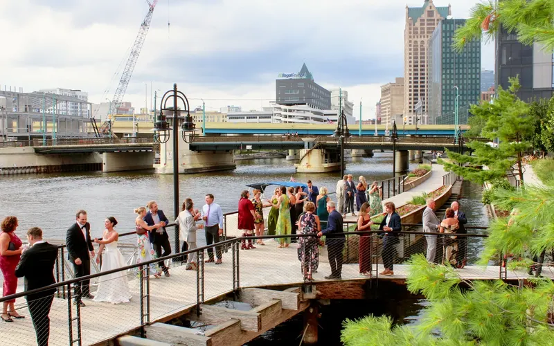 Guests gathered on the Milwaukee Riverwalk, with the river and downtown buildings behind them