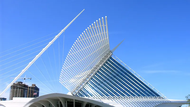 The white steel wings of the Milwaukee Art Museum's Quadracci Pavilion raised against a blue sky, with the glass prow below