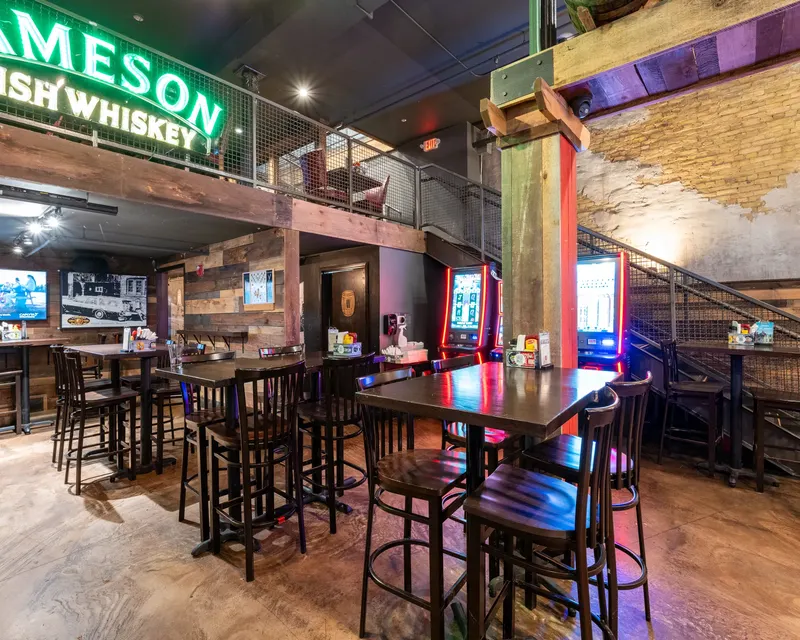High tables under the Jameson neon sign inside Oak Barrel, with the bar and its taps beyond