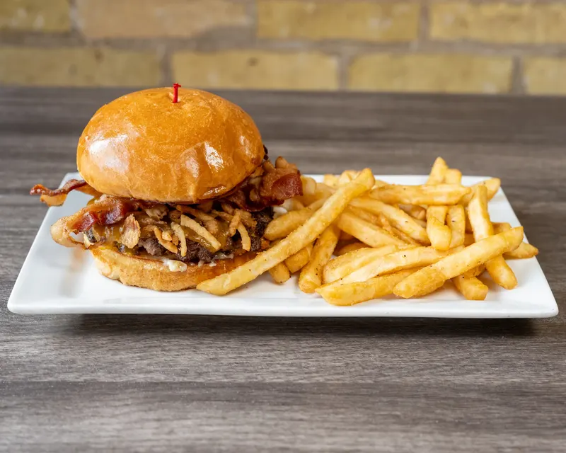 The bacon jam smash burger with fries on a white plate