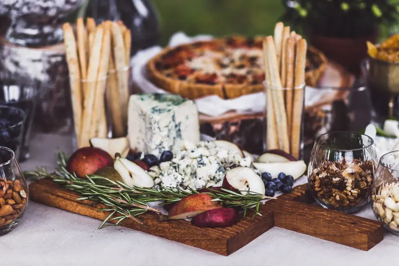 A grazing board of cheeses, pears, walnuts and breadsticks