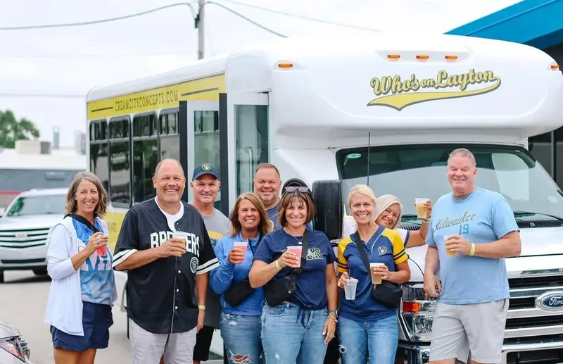 Guests in Brewers gear holding drinks in front of the Who's on Layton shuttle bus